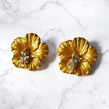 Load image into Gallery viewer, Gold hibiscus earrings on a marble countertop