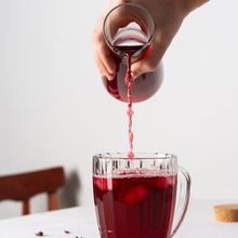 Load image into Gallery viewer, Pouring hibiscus tea from a glass pitcher
