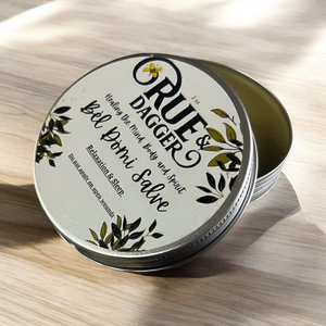 Tin of Rue & Dagger Balm on a wooden surface