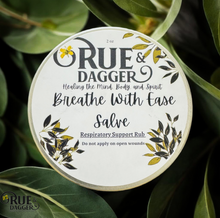 Load image into Gallery viewer, Round container of Rue &amp; Dagger Salve with green leaves in the background
