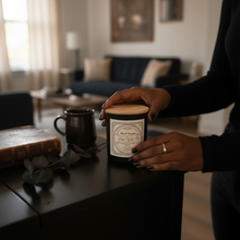 Load image into Gallery viewer, Person holding a candle in a cozy living room setting.
